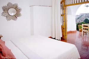 a bedroom with a white bed and a mirror at Posada de la Mision, Hotel Museo y Jardin in Taxco de Alarcón
