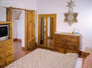 a living room with a tv and a wooden dresser at Posada de la Mision, Hotel Museo y Jardin in Taxco de Alarcón