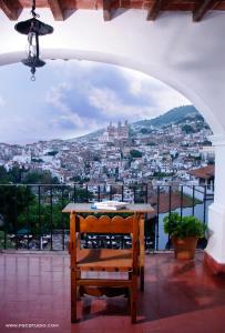 a chair sitting on a balcony with a view of a city at Posada de la Mision, Hotel Museo y Jardin in Taxco de Alarcón