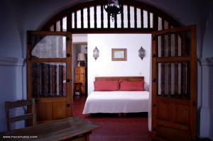 a bedroom with a large bed with red pillows at Posada de la Mision, Hotel Museo y Jardin in Taxco de Alarcón