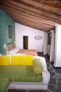 a bedroom with a large bed with yellow pillows at Posada de la Mision, Hotel Museo y Jardin in Taxco de Alarcón
