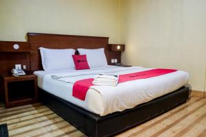 a bedroom with a large bed with a red blanket on it at RedDoorz Plus near DC Mall Batam in Nagoya