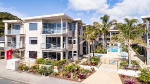 an image of an apartment building with palm trees at Edgewater Palms Apartments in Paihia