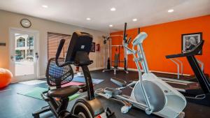 a gym with orange walls and a room with a exercise bike at Best Western Yuba City Inn in Yuba City