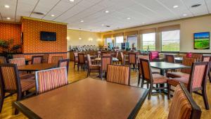 a restaurant with tables and chairs and a television at Best Western Shepherdsville in Shepherdsville