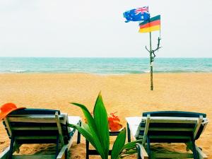 two chairs and a table on the beach with a flag at Sri Lancashire Guest House in Bentota