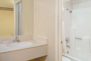 a white bathroom with a sink and a shower at Travelodge by Wyndham San Clemente Beach in San Clemente