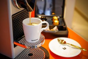 a cup of coffee is being brewed in a microwave at Boutiquehotel Das Tyrol in Vienna