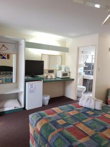 a room with a bed and a kitchen with a microwave at Harbour Lodge Motel in Gladstone