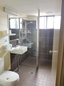 uma casa de banho com um chuveiro, um WC e um lavatório. em Harbour Lodge Motel em Gladstone