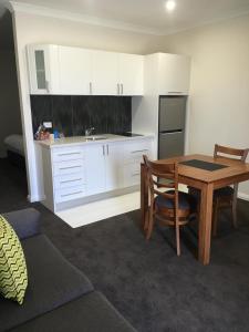 a kitchen with white cabinets and a table and a sink at Red Earth Motel in Broken Hill