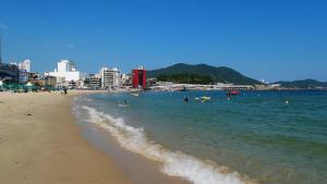 a beach with a group of people in the water at V Motel Songdo in Busan