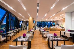 un comedor con mesas, sillas y ventanas en Ascott Raffles City Beijing, en Beijing