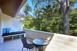 un balcón con mesa, sillas y un árbol en Tea Trees, en Noosa Heads