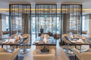 a restaurant with two tables and chairs and glass walls at Strandhotel Fontana in Timmendorfer Strand