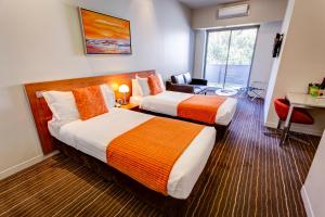 una camera d'albergo con 2 letti e una scrivania di Mantra Charles Hotel a Launceston