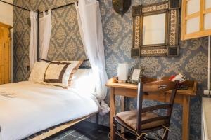 Schlafzimmer mit einem Bett und einem Schreibtisch mit einem Spiegel in der Unterkunft Hotel Berneau in Berneau