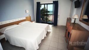 - une chambre avec un grand lit blanc et une fenêtre dans l'établissement La Cabaña, à Peñíscola