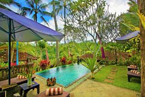 a swimming pool in a garden with an umbrella at The Mahogany Villa in Tegalalang