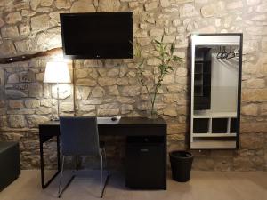 a desk with a television on a stone wall at Les Muntades in Jorba