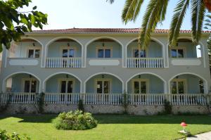 a large white house with a palm tree at Hotel Villa Basil in Tsilivi