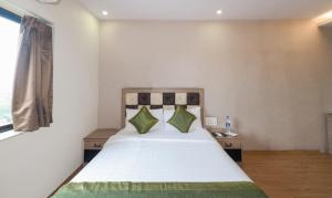 una camera da letto con un grande letto bianco con cuscini verdi di Treebo Trend Pal Comfort a Jamshedpur