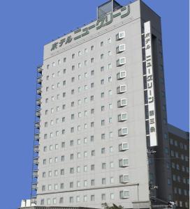 een hoog wit gebouw met een bord erop bij Hotel New Green Tsubame Sanjo in Sanjo
