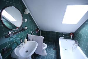 a green tiled bathroom with a sink and a mirror at Sára Vendégház in Szentes
