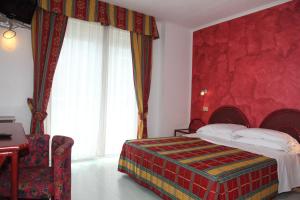 1 dormitorio con cama y pared roja en Hotel Soraya en Lignano Sabbiadoro