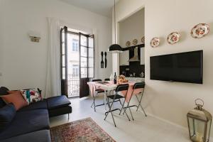 een woonkamer met een tafel en een televisie bij Suite La Piazza by Wonderful Italy in Siracusa