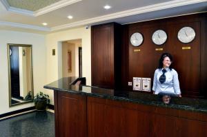 a woman standing behind a counter in a room with clocks at Aparthouse Borovo in Sofia