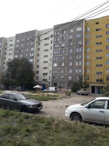 two cars parked in a parking lot in front of a large building at Квартира in Temirtaū