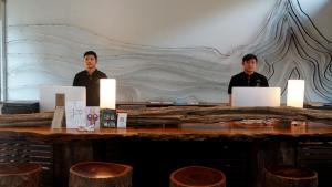 two men standing behind a table with two laptops at Bamboori Boutique Resort in Chiang Mai