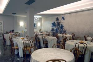 モンテカティーニ・テルメにあるHotel Brasileのダイニングルーム(テーブル、椅子、白いテーブルクロス付)