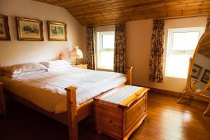 a bedroom with a large bed and two windows at Barnesmore Cottage in Barnesmore