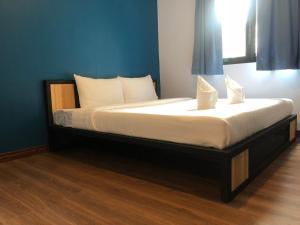 1 cama con sábanas blancas y almohadas en una habitación en Thyme Xeriscape Hostel, en Kanchanaburi