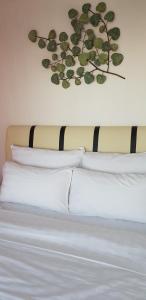 a bed with white pillows and a plant on the wall at The Wharf in Semporna