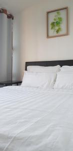 a white bed with white sheets and a picture on the wall at The Wharf in Semporna