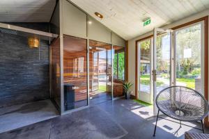 a room with glass doors and a chair at Hôtel Restaurant & Spa Plaisir in Le Bois-Plage-en-Ré