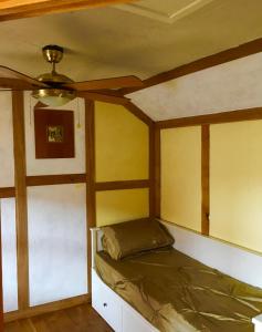 Cama en habitación con ventilador de techo en The Rabbit Hole, en Glastonbury