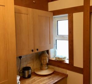 a kitchen with a bust sitting on a counter next to a window at The Rabbit Hole in Glastonbury