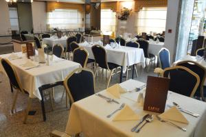 uma sala de jantar com mesas e cadeiras com toalha de mesa branca em Capri Hotel Suites em Amã