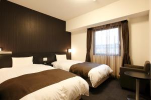 Dormy Inn Mishima في ميشيما: غرفة فندقية بسريرين ونافذة