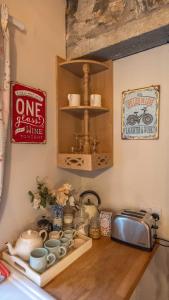 a kitchen counter with a shelf with cups and dishes at Glamping Bothie in Inverurie