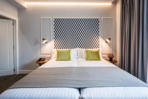 ein Schlafzimmer mit einem großen weißen Bett mit grünen Kissen in der Unterkunft Intelier Victoria in San Sebastián