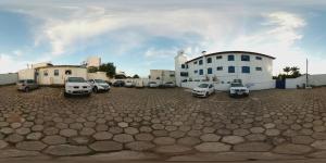 un estacionamiento con autos estacionados frente a un edificio en Hotel Vila Mineira, en Oliveira