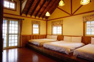 een slaapkamer met 3 bedden in een kamer met ramen bij Euro Country Villa in Renai