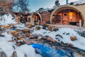 una cabaña de madera en la nieve con un arroyo delante en Maximus Resort en Brno