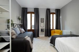 een slaapkamer met 2 bedden en een gele stoel bij tuGuest San Gil Apartments in Granada