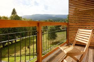 eine Holzterrasse mit einem Stuhl auf dem Balkon in der Unterkunft Aparthotel Cristal Resort Szklarska Poręba by Zdrojowa in Szklarska Poręba